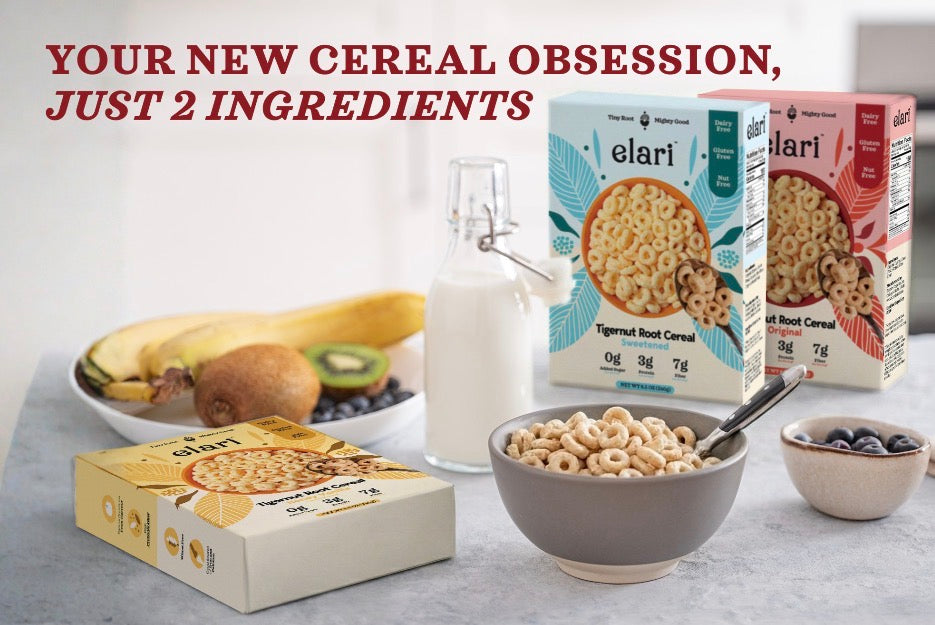Elari cereal boxes with a bowl of cereal, milk, and fruit on a table.